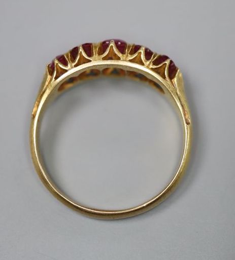 A yellow metal and graduated five stone ruby set half hoop ring,